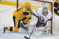 Pittsburgh Penguins' Zach Aston-Reese, left, slides into the goal behind New York Islanders goaltender Semyon Varlamov, right, during the first period in Game 2 of an NHL hockey Stanley Cup first-round playoff series in Pittsburgh, Tuesday, May 18, 2021. (AP Photo/Gene J. Puskar)