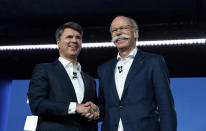 BMW CEO Harald Krueger, left, and Mercedes-Benz CEO Dieter Zetsche of Daimler, right, shake hands at a press conference in Berlin, Germany, Friday, Feb. 22, 2019. Automakers Daimler and BMW are formally launching their joint venture in services that make it possible to use their cars without necessarily owning one. (Bernd von Jutrczenka/dpa via AP)