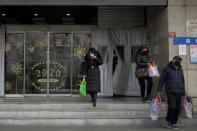 Customers wearing masks walk out of Alibaba's Hema Fresh chain store after shopping during the Chinese Lunar New Year holiday in Beijing