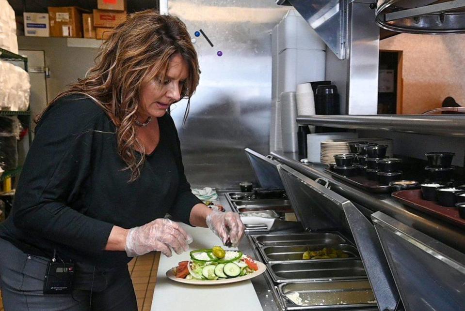 DeeDee Jovaras, co-owner of Mr. Gyro’s, demonstrates how the dishes are prepared in the kitchen, including this Greek salad, topped with an olive.