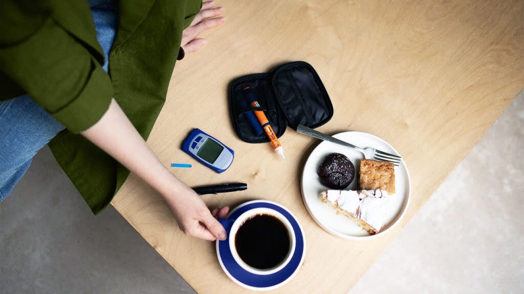 photo of glucose monitor next to cup of coffee and plate of sweets