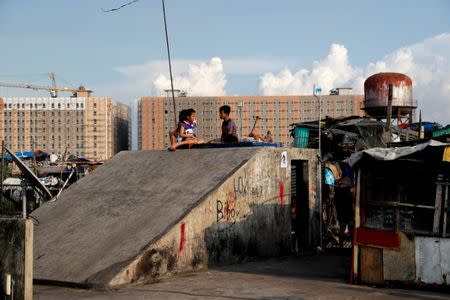 Residents rest on the rooftop of Vitas Tenement, a government housing building, overlooking a new residential condominium building in Tondo, Manila, Philippines, May 8, 2018. REUTERS/Erik De Castro