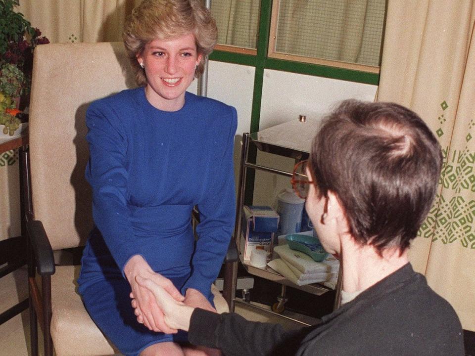 Diana shakes the hand of a person with AIDS in 1987.