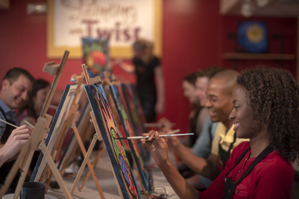 This 2019 photo provided by Painting with a Twist shows a group taking part in a Painting with a Twist event in Mandeville, La. In recent years, the interactive painting industry has become a global sensation. Around the world, adults can spend their nights out learning to paint in a relaxed, BYOB setting. Thousands of franchises exist to help us all unleash our inner creative. (Painting with a Twist via AP)