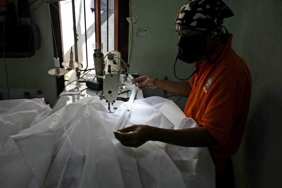 In this Thursday, April 2, 2020, photo, a tailor makes hazmat suits at a home garment factory in Depok, Indonesia. When an Indonesian businesswoman Maryati Dimursi heard from friends working in hospitals that they don't have enough proper protective gear when dealing with suspected COVID-19 patients, she decided to help them by crowdfunding to produce proper hazmat suits for distribution to various hospitals in the country. (AP Photo/Dita Alangkara)