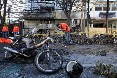 A forensic police officer takes pictures of debris near burned motorcycles following a blast at the Pentecost Church Central Surabaya (GPPS), in Surabaya, Indonesia May 13, 2018. REUTERS/Beawiharta