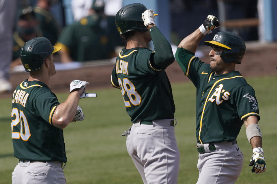 Oakland Athletics' Ramon Laureano, right, celebrates after hitting a three-run home run that scored Mark Canha (20) and Matt Olson (28) during the second inning of Game 4 of a baseball American League Division Series against the Houston Astros in Los Angeles, Thursday, Oct. 8, 2020. (AP Photo/Ashley Landis)