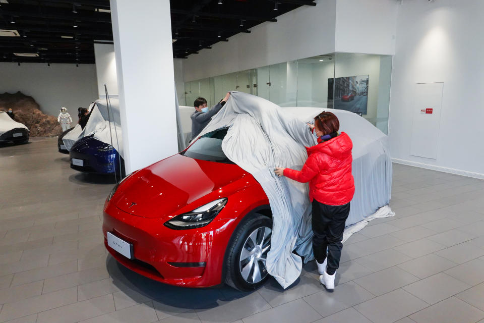 SHANGHÁI, CHINA - 18 DE ENERO: Los clientes quitan la tela que cubre su nuevo vehículo crossover compacto Modelo Y fabricado en China en una sala de exposición de Tesla el 18 de enero de 2021 en Shanghái, China. (Foto de VCG/VCG a través de Getty Images)