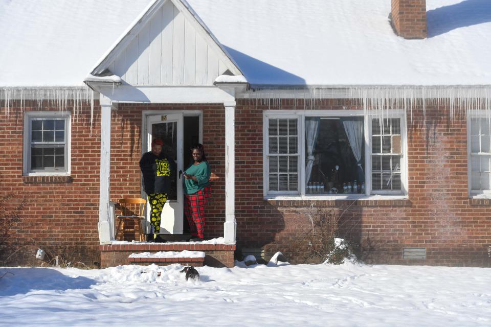 Teresa and Tinia Mastowitz becken their dog Cupcake to come back inside the house after using the bathroom as snow blankets Jackson, Tenn., on Tuesday, Jan. 16, 2024.