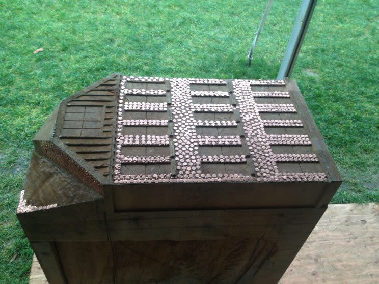 Carving of a residential school, covered in copper nails