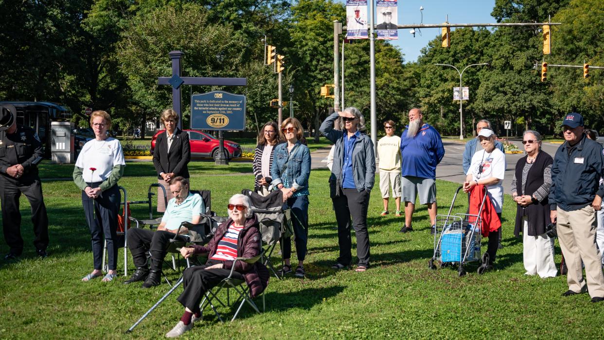 The audience listens curing a 9/11 remembrance ceremony at Utica's 9/11 memorial on the Memorial Parkway on Sept. 11, 2024. Participants said the crowd has slowly dwindled each year. But two family members of victims came: Shirley Felt, seated at center, whose son Edward died in  Shanksville, Pennsylvania; and Vanessa Graham, standing at left with a carnation, whose brother Don Kauth died at the World Trade Center.