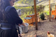 <p>The multi-tasking mom carries one of her kids while feeding the family chickens. </p>