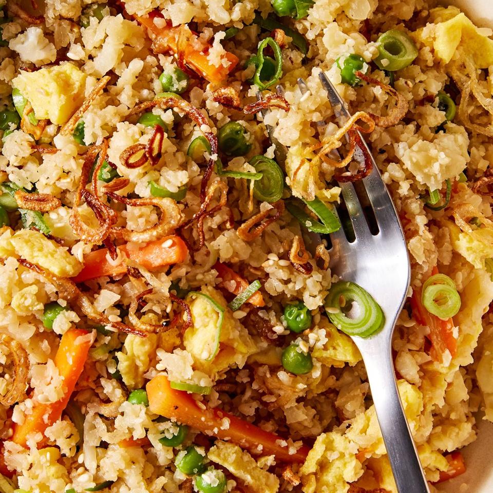 cauliflower fried rice with carrots, green onion, and eggs topped with sesame seeds