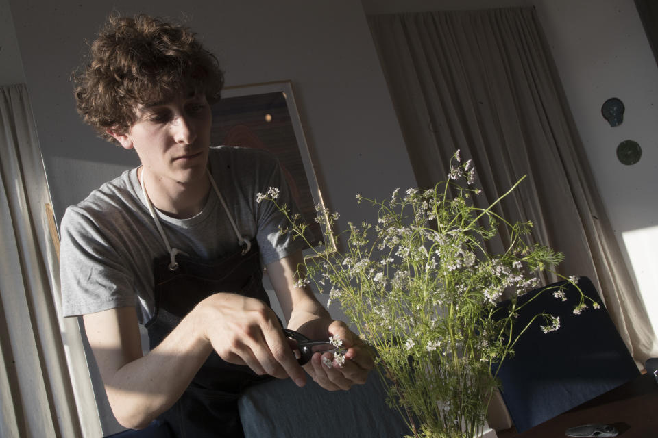 In this May 17, 2019 photo, Jonah Reider trims flowering cilantro to use in a beef tartare toast appetizer during a Pith dinner in New York. He’s managed to earn a living as an innovative cook with no formal training, hired by corporations and individuals to take his unique pop-up creations around the world, from Italy and Japan to Australia and the United States. (AP Photo/Mary Altaffer)