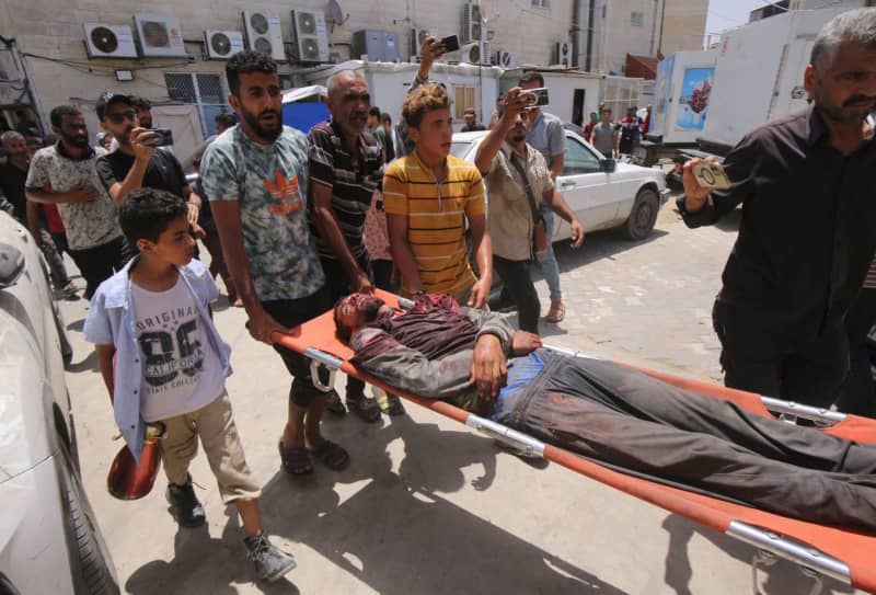 Palestinians carry an injured man to Al-Aqsa Martyrs' Hospital following simultaneous Israeli attacks on Nuseirat Refugee Camp, al-Bureij Refugee Camp and al-Maghazi Refugee Camp.  Israeli special forces rescued four hostages in broad daylight on Saturday in the Nuseirat refugee district in the central Gaza Strip after 246 days in captivity, the army said.  Omar Naaman/dpa