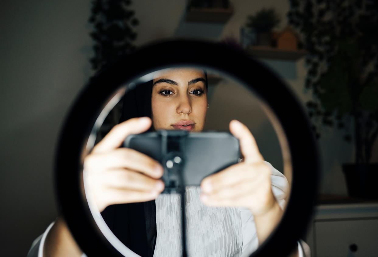 Female vlogger adjusting mobile phone while vlogging at home