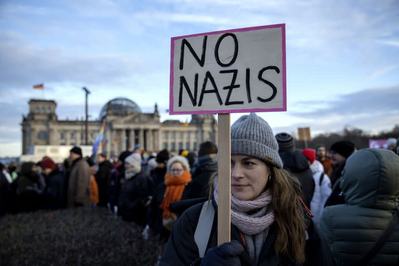 People gather as they protest against the AfD party and right-wing extremism in front of the Reichstag building in Berlin, Germany.