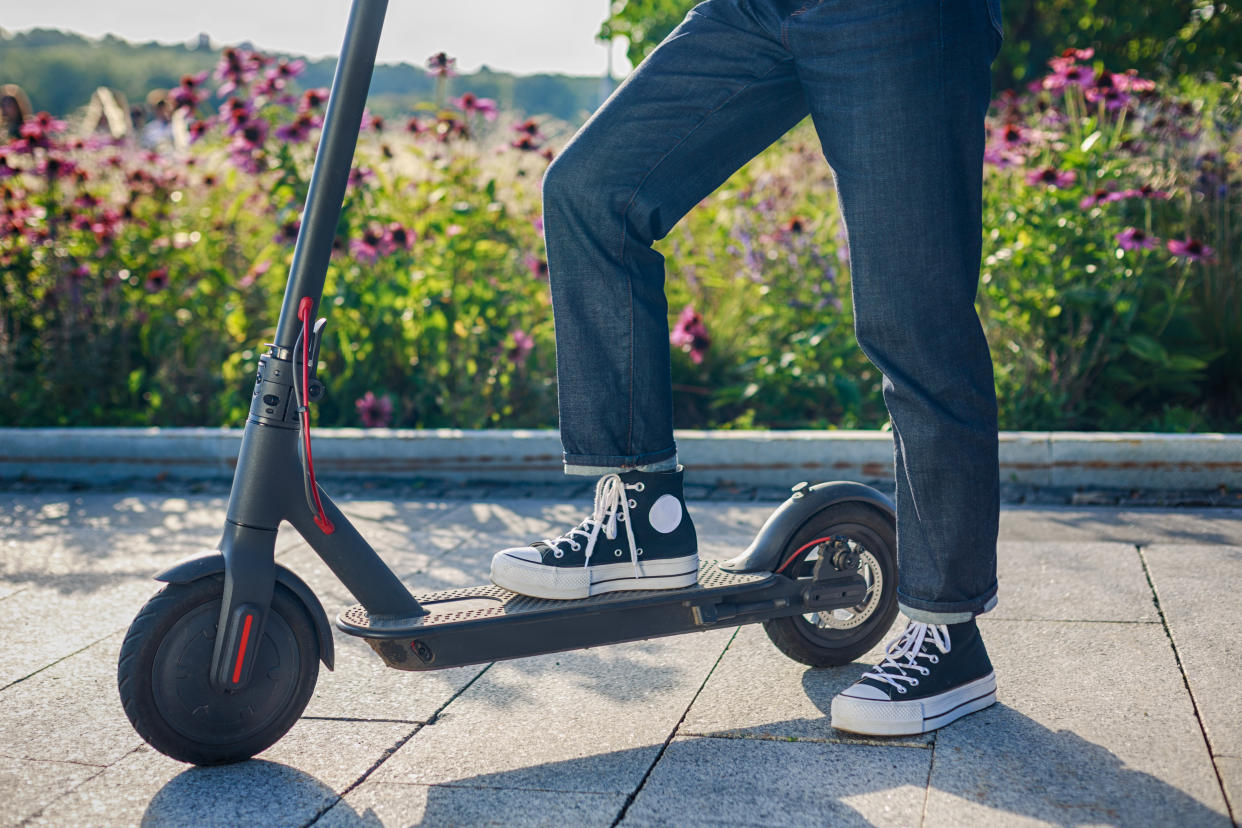 girl is taking her electric scooter denim style flowers behind her