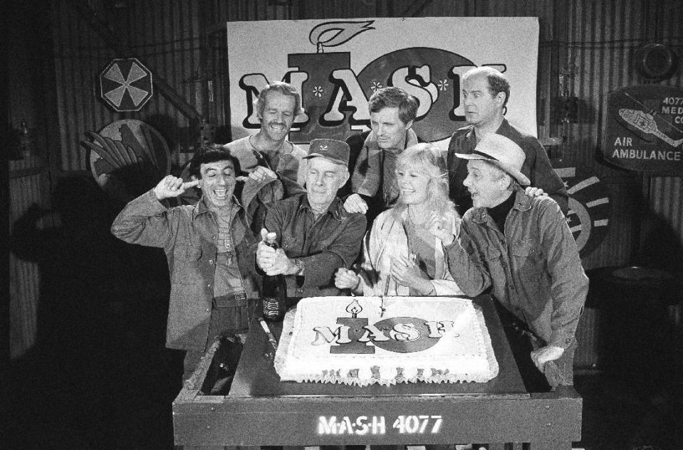 FILE- IN this Oct. 22, 1981, file photo, Jamie Farr, left, plugs his ears, as cast members of the "M*A*S*H" television series cast from front left, Harry Morgan, Loretta Swit, William Christopher, and from back from left, Mike Farrell Alan Alda and David Ogden Stiers celebrate during a party on the set of the popular CBS program in Los Angeles. Christopher died Saturday, Dec. 31, 2016. He was 84. (AP Photo/Huynh, File)