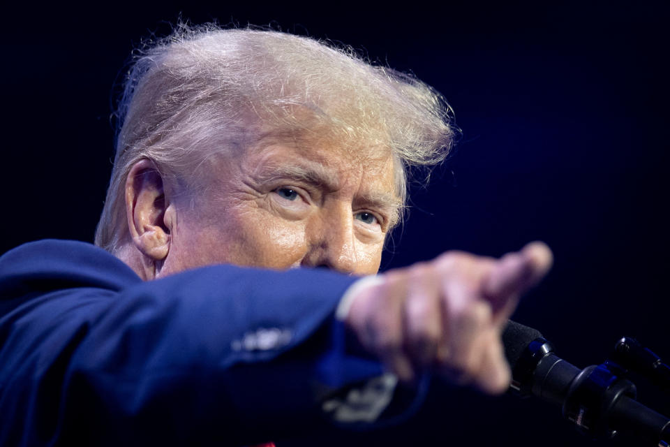 Former President Donald Trump points toward the audience as he speaks at a podium.