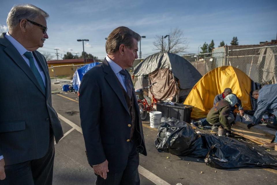 La leyenda del beisbol Steve Garvey, a la derecha, y el ex alguacil de Sacramento John McGinness, a la izquierda, recorren un campamento de personas sin hogar en Sacramento, el miércoles 17 de enero de 2024. Garvey, candidato republicano al Senado federal, dijo que quiere que se rindan cuentas sobre cómo se gasta el dinero para ayudar a los indigentes.