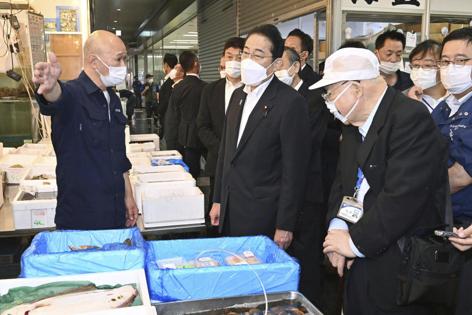 Japan's Prime Minister Fumio Kishida, center, speaks with a worker as he inspects Toyosu fish market in Tokyo Thursday, Aug. 31, 2023. Kishida visited the fish market to highlight fish safety and assess the impact of China's ban on Japanese seafood. (Kyodo News via AP)