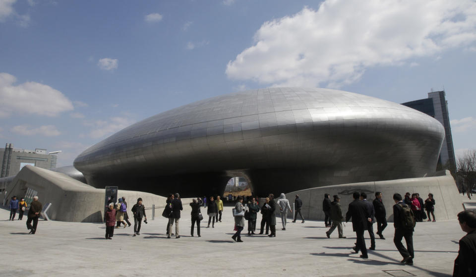 Visitors are dwarfed by Dongdaemun Design Plaza in Seoul, South Korea, Friday, March 21, 2014. The $450 million building funded by Seoul citizen's tax money finally opened to public on Friday after years of debates about transforming a historic area with an ultra-modern architecture.(AP Photo/Ahn Young-joon)
