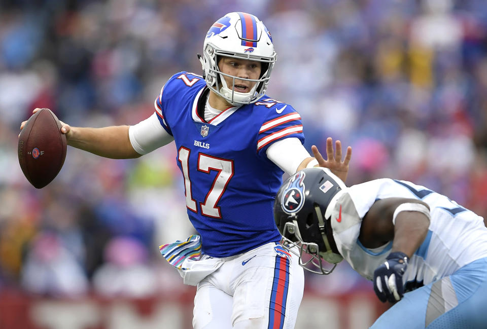 FILE- In this Oct. 7, 2018, file photo, Buffalo Bills quarterback Josh Allen, left, tries to avoid a tackle from Tennessee Titans linebacker Sharif Finch during the second half of an NFL football game in Orchard Park, N.Y. Many teams think it's best to throw rookie QBs right into the fire to learn on the job. Others prefer to gradually work them into the offense. Then, there are some who believe it's more beneficial to have them grab a cap and a clipboard and take it all in from the sideline. (AP Photo/Adrian Kraus, File)