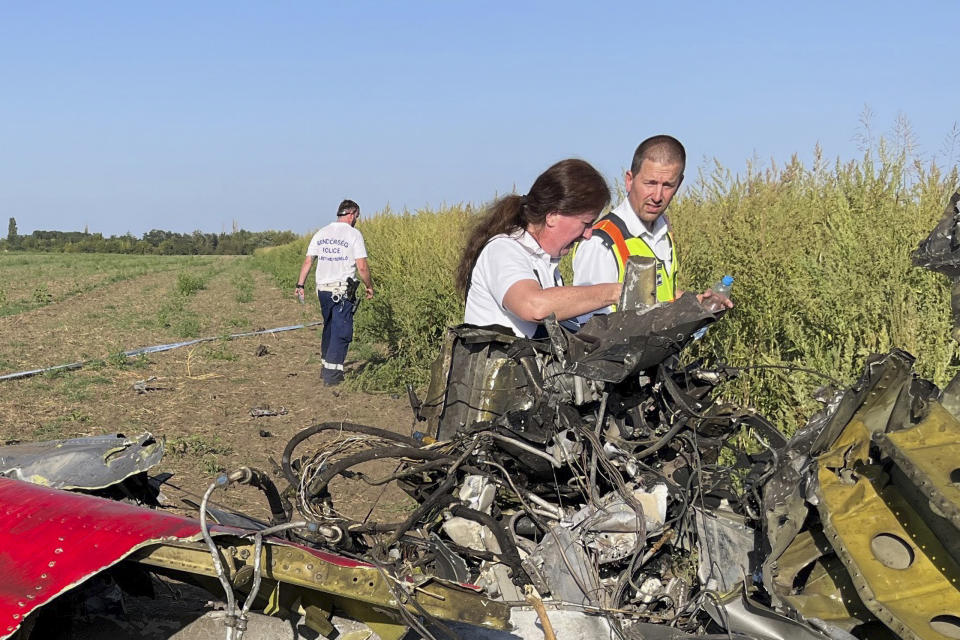 This photo released by the Hungarian Police, shows police investigators examining wreckage at a plane crash site in the Borgond area, Hungary, Sunday, Sept. 10, 2023. Police say a small propeller-driven plane has crashed during an airshow in central Hungary killing two people and seriously injuring three people on the ground at the Borgond air show in Fejer county. (Hungarian Police via AP)