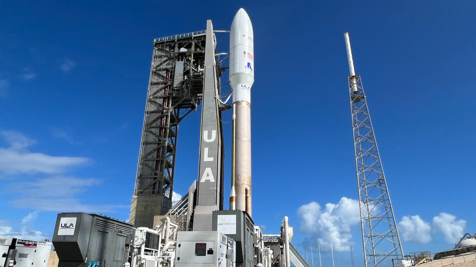 a brown and white rocket stands with a blue sky in the background.