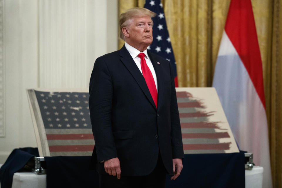 President Donald Trump stands in front of a 48-star flag flown on a U.S. Naval vessel during the D-Day invasion during a ceremony in the East Room of the White House, Thursday, July 18, 2019, in Washington. The flag, presented by its Dutch owners to Trump, will be given to the Smithsonian's National Museum of American History. The vessel was control vessel Landing Craft, Control 60 (LCC 60). (AP Photo/Carolyn Kaster)