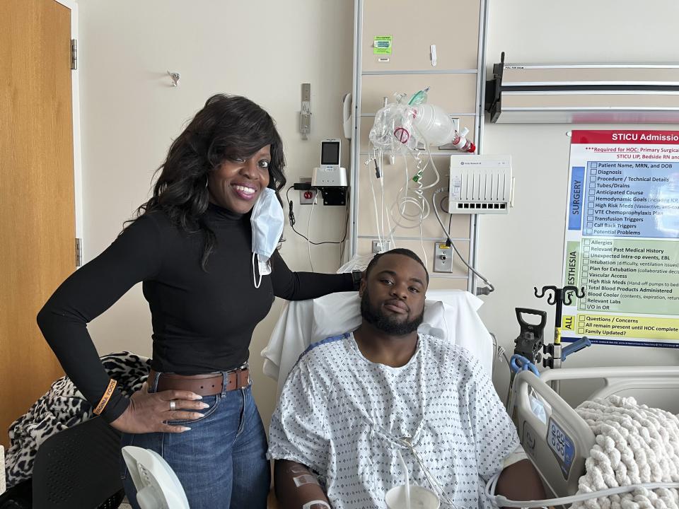 This image provided by Brenda Hollins by Gordon McKernan shows Mike Hollins, right, and his mother, Brenda Hollins, at University of Virginia Medical Center in Charlottesville, Va., on Wednesday, Nov. 17, 2022. Mike Hollins was shot and wounded on the school’s campus on Sunday, Nov. 13. Three of his teammates on the university’s football team were fatally shot during the incident. (Brenda Hollins and Gordon McKernan via AP)