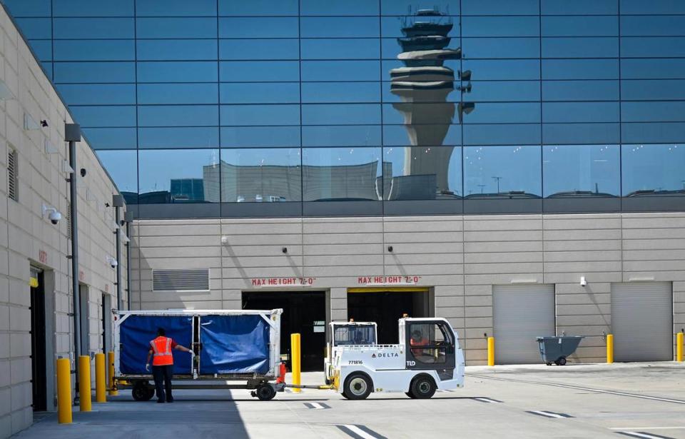 The air traffic control tower is reflected in the terminal as a tug truck moves a baggage cart at Kansas City International Airport.