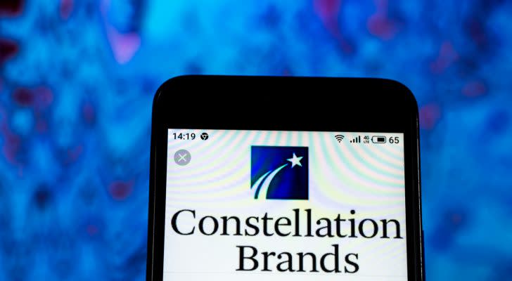 Constellation Brands logo on a phone screen in front of a blue and purple background. STZ stock.