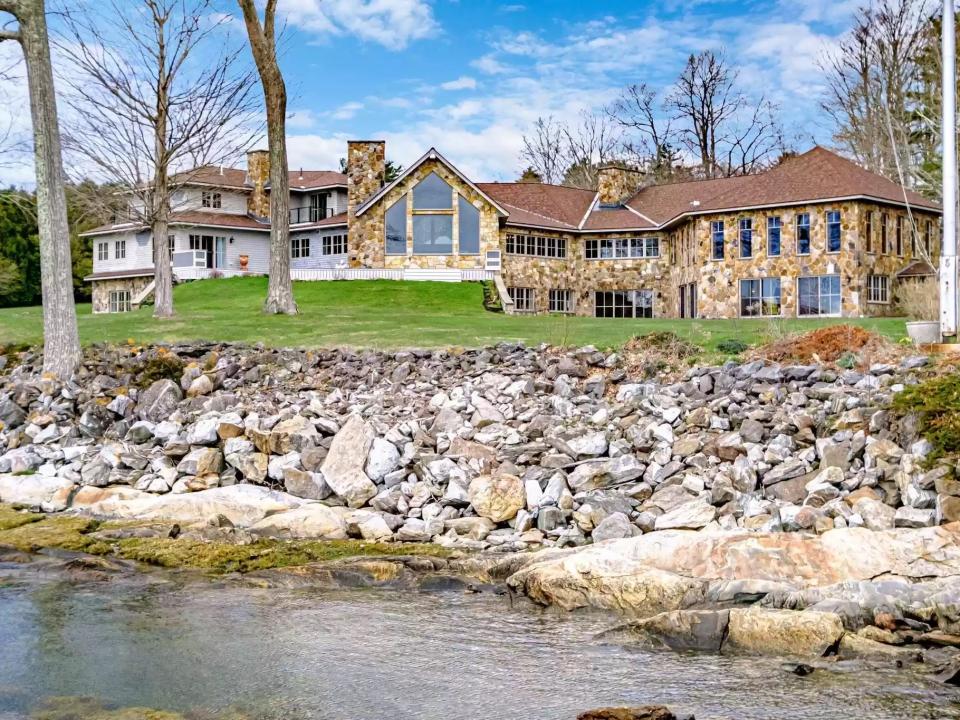 home with a creek, rocks, and autumn trees in Maine