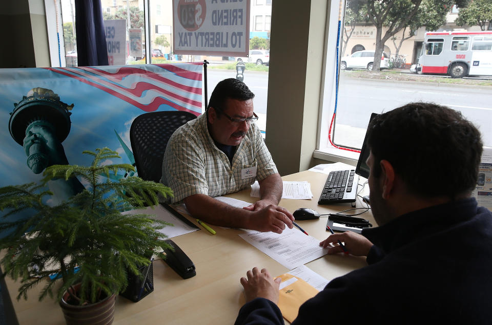 Tax preparer Robert Romero (L) helps a client prepare his income tax at the Liberty Tax Service in San Francisco, California.  Tax effective date is April 18, 2023. (Credit: Justin Sullivan/Getty Images)