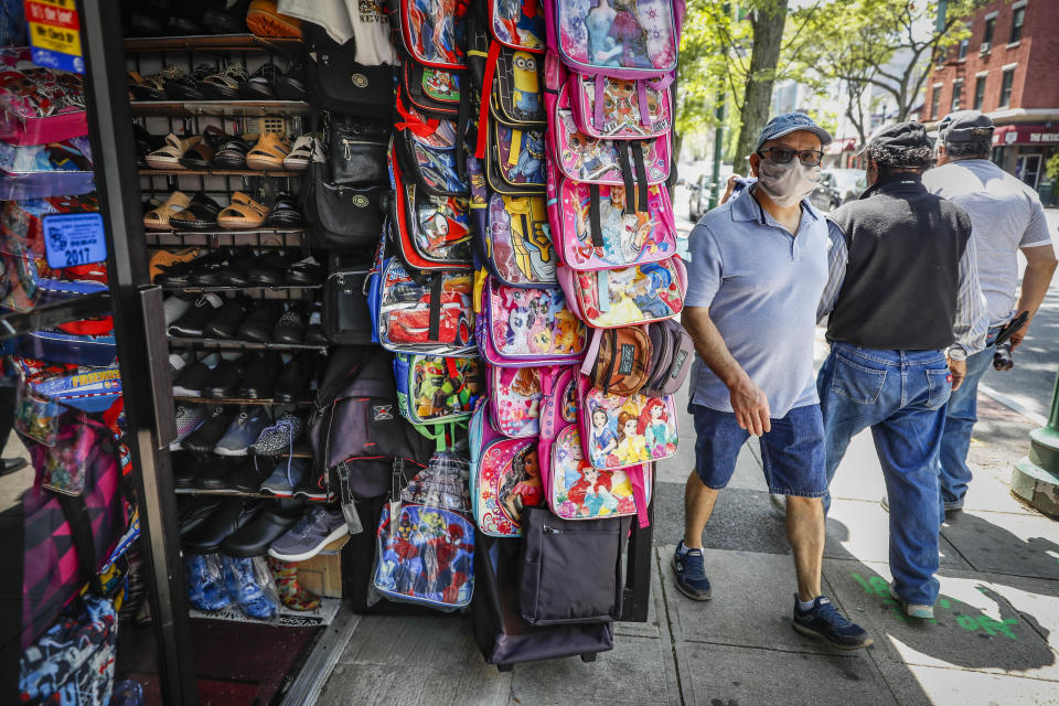 Pedestrians wearing personal protective equipment pass a variety store on Main Street, Tuesday, May 26, 2020, in New Rochelle, N.Y. (AP Photo/John Minchillo)
