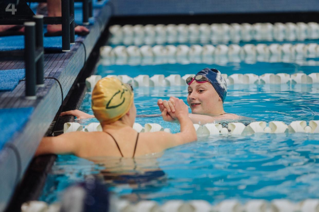 Emma Guter of Great Falls High (blue cap) high-fives CMR's Taylor Kolsch after a race at the crosstown meet on Tuesday at the Great Falls High Pool.