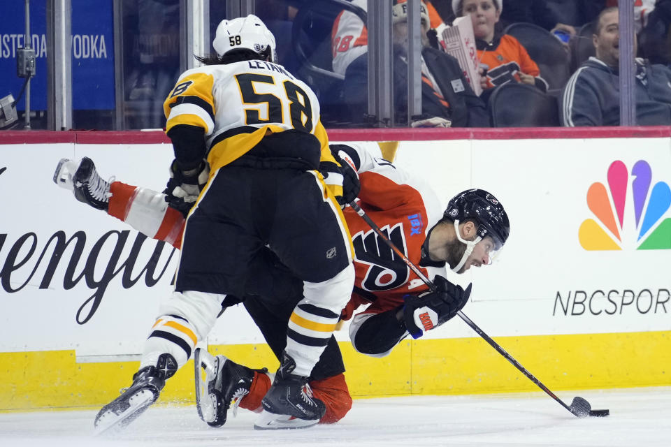 Philadelphia Flyers' Scott Laughton, right, is hit by Pittsburgh Penguins' Kris Letang during the second period of an NHL hockey game, Monday, Dec. 4, 2023, in Philadelphia. (AP Photo/Matt Slocum)