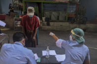 Health workers record migrant workers ahead of collecting nasal swab samples from them to test for COVID-19 in Samut Sakhon, south of Bangkok, Thailand, Sunday, Dec. 20, 2020. Thailand on Sunday reported a few new local infections, a day after identifying more than 500 cases south of Bangkok in a country that had largely brought the pandemic under control. (AP Photo/ Chalida Ekvitthayavechnukul)