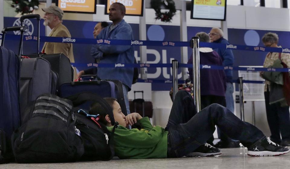 Seven-year-old Jordan Knowles rests his head against his family's luggage, who were rebooking their JetBlue flight back home to the Bahamas, at Logan Airport, Monday, Jan. 6, 2014, in Boston. JetBlue announced that they would halt operations in Boston, New York and New Jersey later in the afternoon, to rest their crews and give it time to service aircraft, due to flight delays and cancellations. Heavy rains in the East, and sub-zero temperatures in the Midwest, threw airlines and travel plans into havoc. (AP Photo/Charles Krupa)