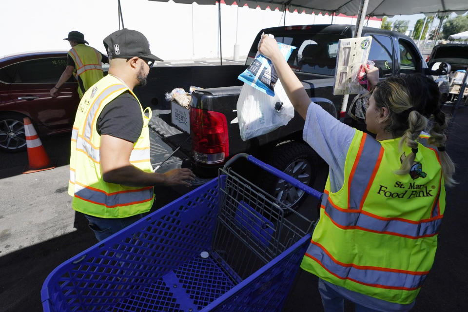 Volunteers fill up vehicles with food boxes at the St. Mary's Food Bank Wednesday, June 29, 2022, in Phoenix. Long lines are back at food banks around the U.S. as working Americans overwhelmed by inflation turn to handouts to help feed their families. (AP Photo/Ross D. Franklin)