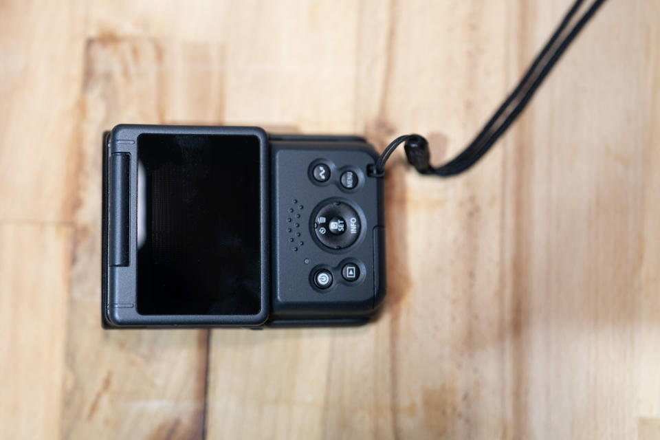 A Canon PowerShot V10 camera on a brown table