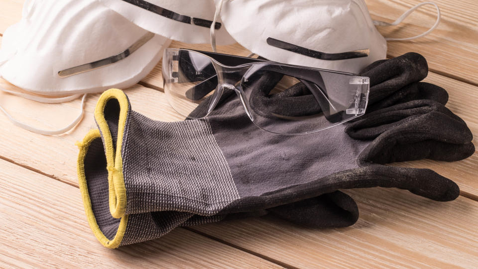 A pair of protective gloves next to goggles and dust masks