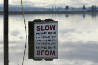 A partially submerged sign is shown near a flooded farm field near Sumas, Wash., Monday, Nov. 29, 2021. People in Sumas, located near the Canadian border, were asked to evacuate voluntarily Saturday night, as communities in the area were still dealing with flooding from a storm earlier in the month. (AP Photo/Elaine Thompson)