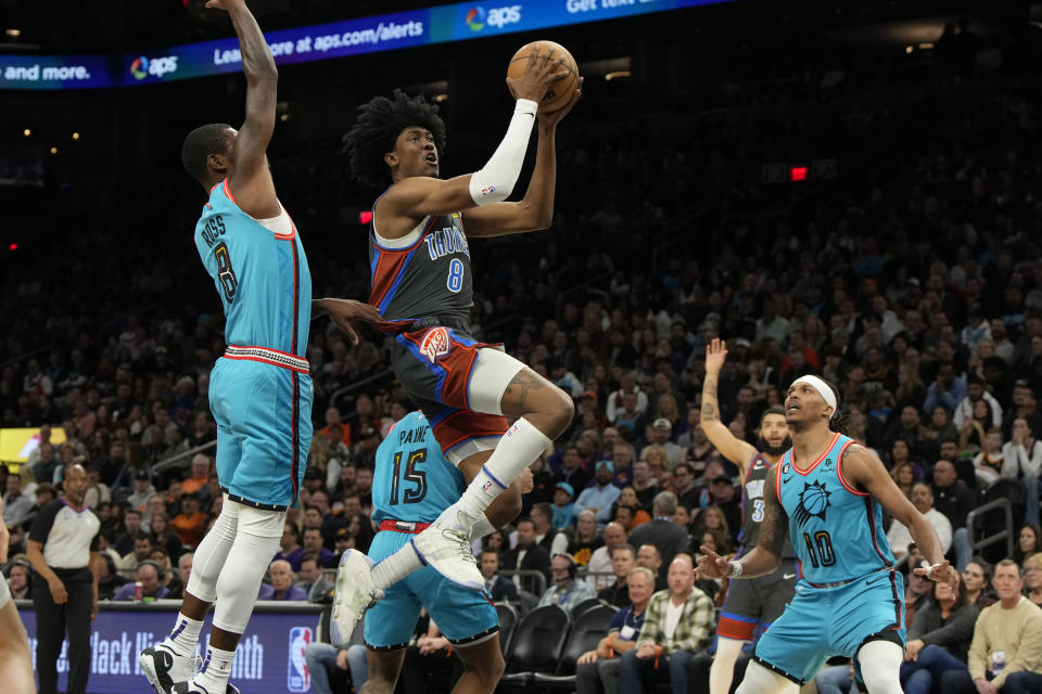 Oklahoma City Thunder forward Jalen Williams, center, drives between Phoenix Suns guards Terrence Ross, left, Cameron Payne (15), and Damion Lee during the first half of an NBA basketball game, Friday, Feb. 24, 2023, in Phoenix. (AP Photo/Rick Scuteri)