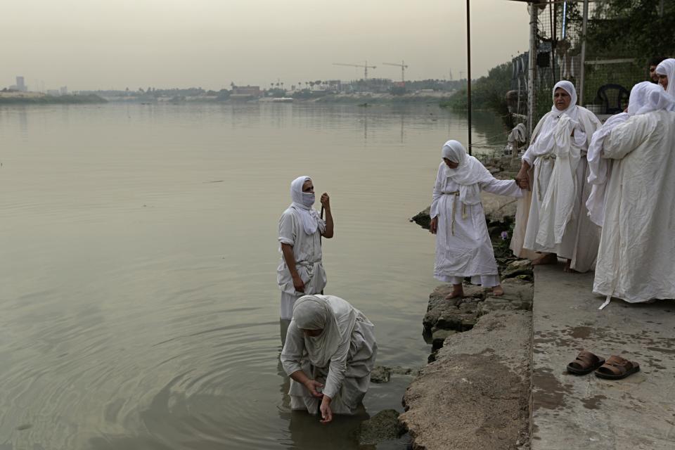 In this Sunday, Oct. 14, 2018 photo, a follower of the obscure and ancient Mandaean faith performs rituals along a strip of embankment on the Tigris River reserved for them, in Baghdad, Iraq. Every Sunday worshippers bathe themselves in the waters to purify their souls. But unlike in ancient times, the storied river that runs through Baghdad is fouled by the smells of untreated sewage and dead carp, which float by in the fast-moving current. (AP Photo/Hadi Mizban)