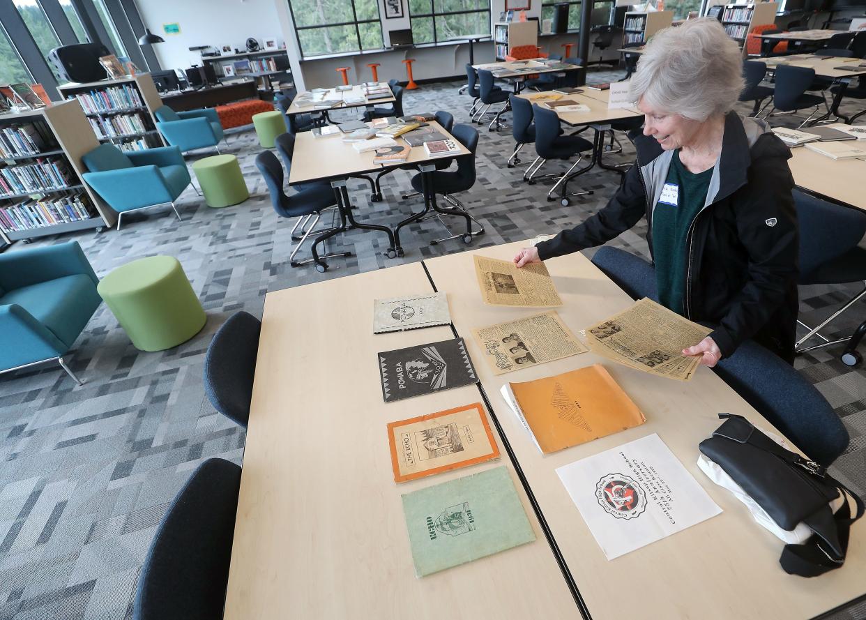 Class of 1960 alum Linda Morton, of Seabeck, places her personal copies of yearbooks that belonged to her parents Jim and Harriet Morton and issues of the student newspaper the Megaphone on one of the tables in the library as she gets ready for the start of the Central Kitsap High School 100 Year Celebration on Monday, March 25, 2024.