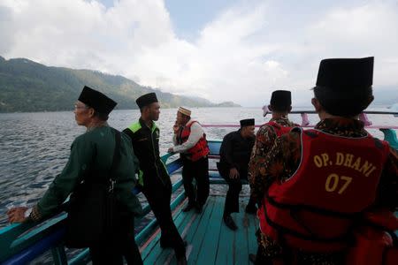 Villagers and Muslim clerics stand on a boat after praying for the missing passengers, after a ferry sank earlier this week in Lake Toba in Simalungun, North Sumatra, Indonesia, June 22, 2018. REUTERS/Beawiharta