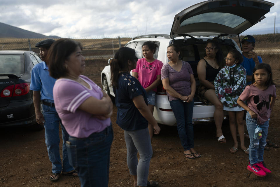 A group of Lahaina, Hawaii, residents who survived the deadly wildfire that devastated their community gather near a checkpoint in hopes to get access to their homes in Lahaina, Hawaii, Wednesday, Aug. 16, 2023. Long before a wildfire blasted through the island of Maui the week before, there was tension between Hawaii's longtime residents and the visitors some islanders resent for turning their beaches, mountains and communities into playgrounds. But that tension is building in the aftermath of the deadliest U.S. wildfire in more than a century.(AP Photo/Jae C. Hong)